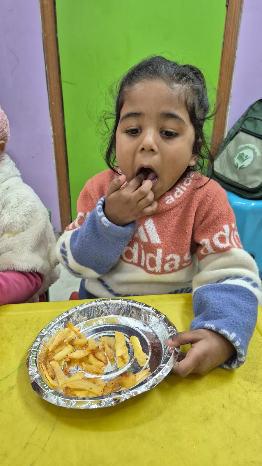 Teacher serving food to children at KinderJoy